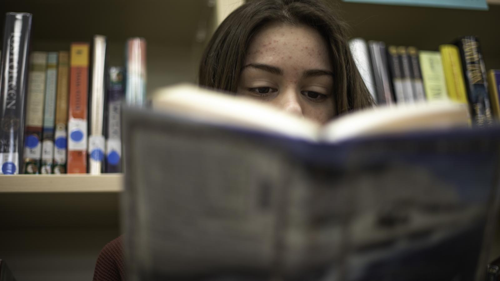 Teenager reading a book in a library