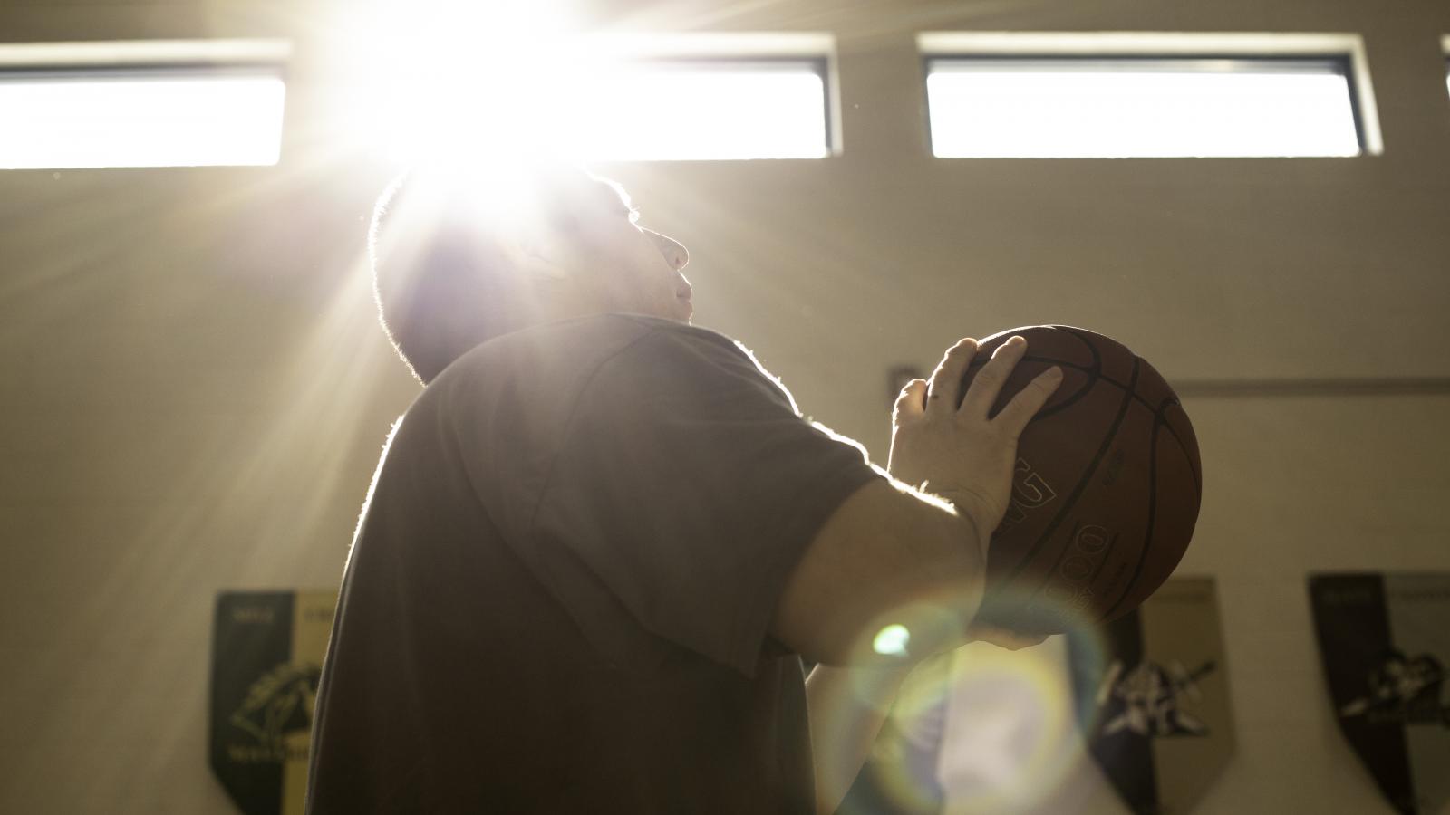 Close-up view of teenager holding a basketball, poised to make a shot 